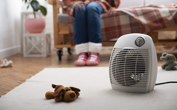 Space heater on a living room floor with a person sitting on a couch